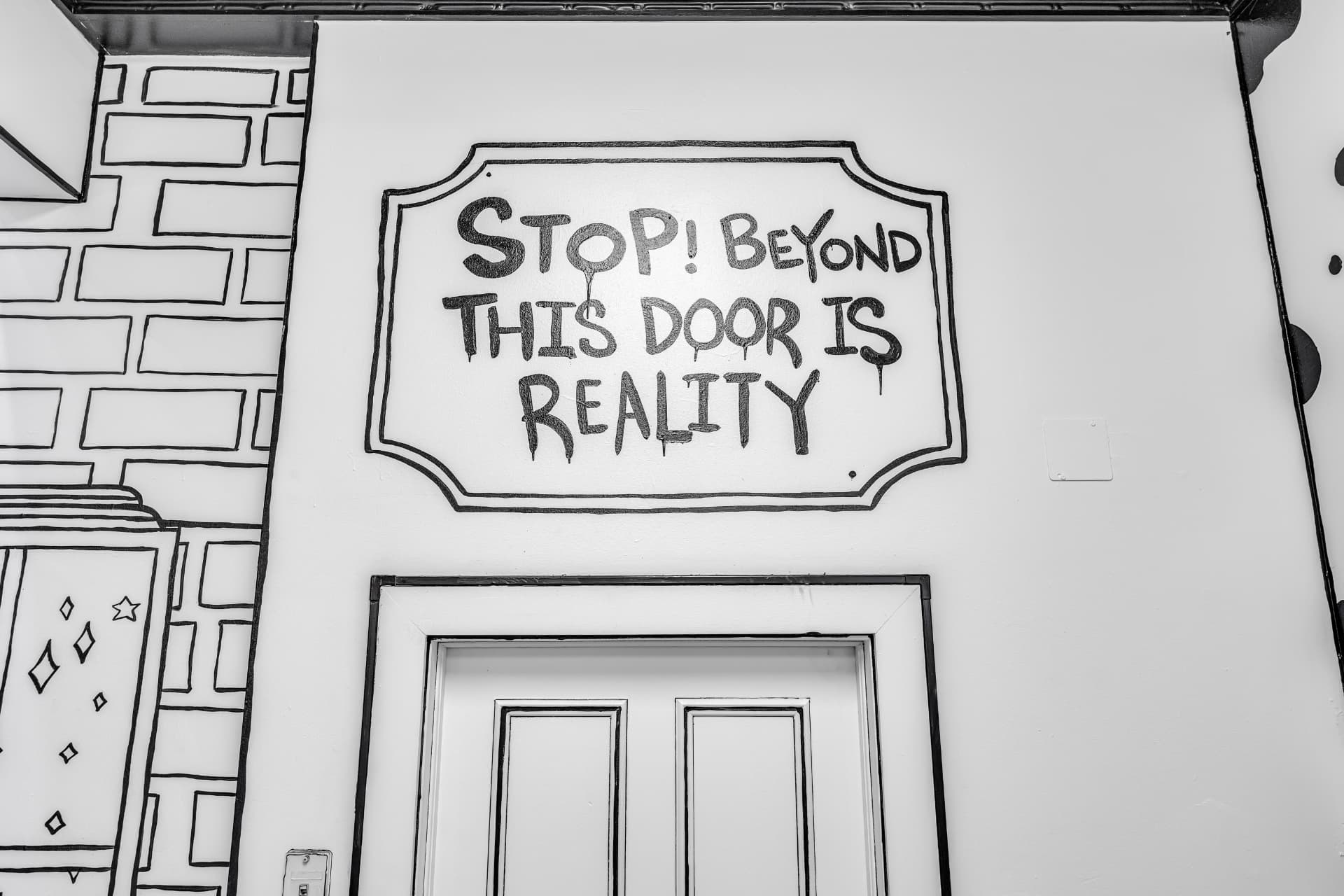 Painted sign reading Stop! Beyond this door is reality