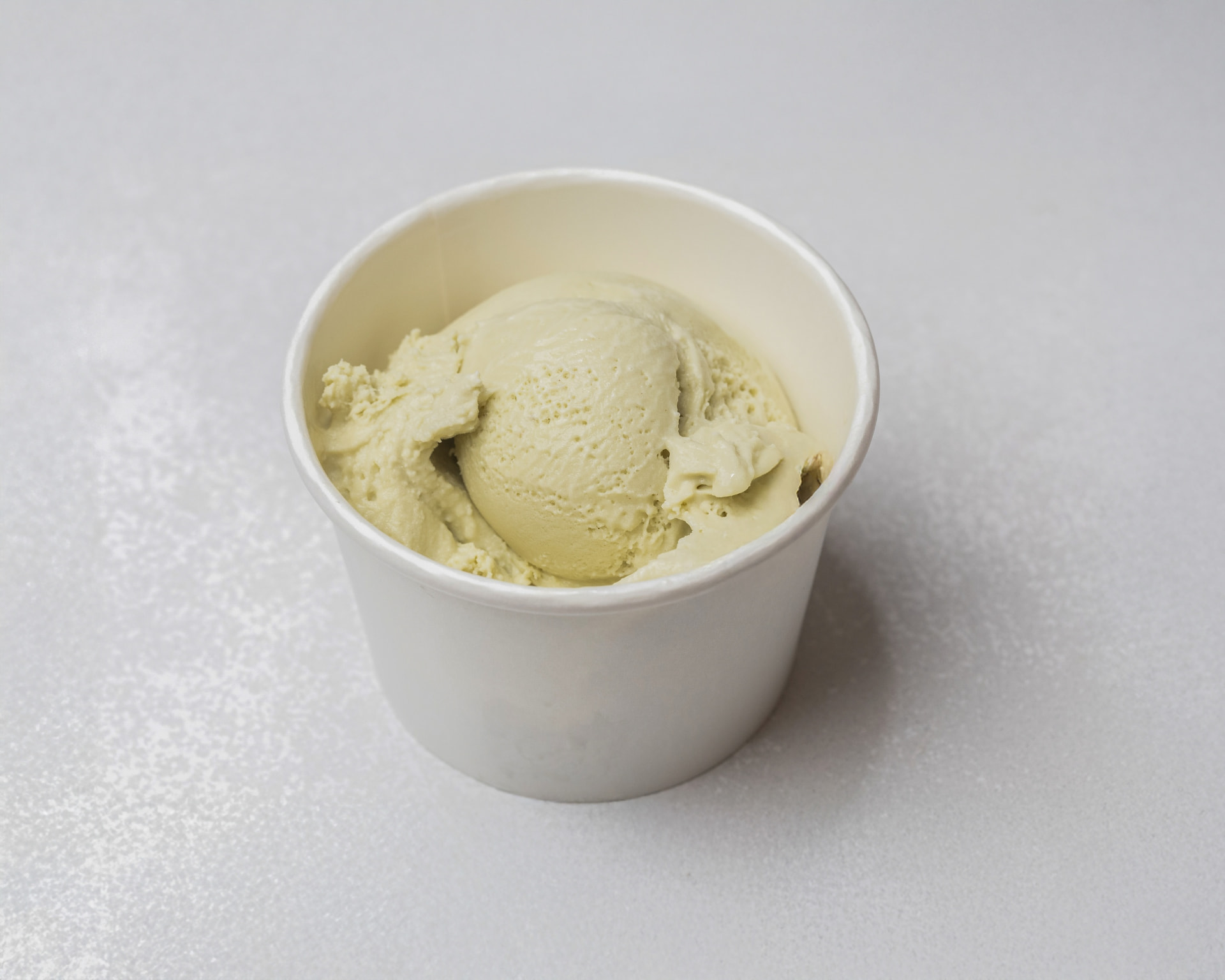 Pale green pistachio ice cream in a white cup
