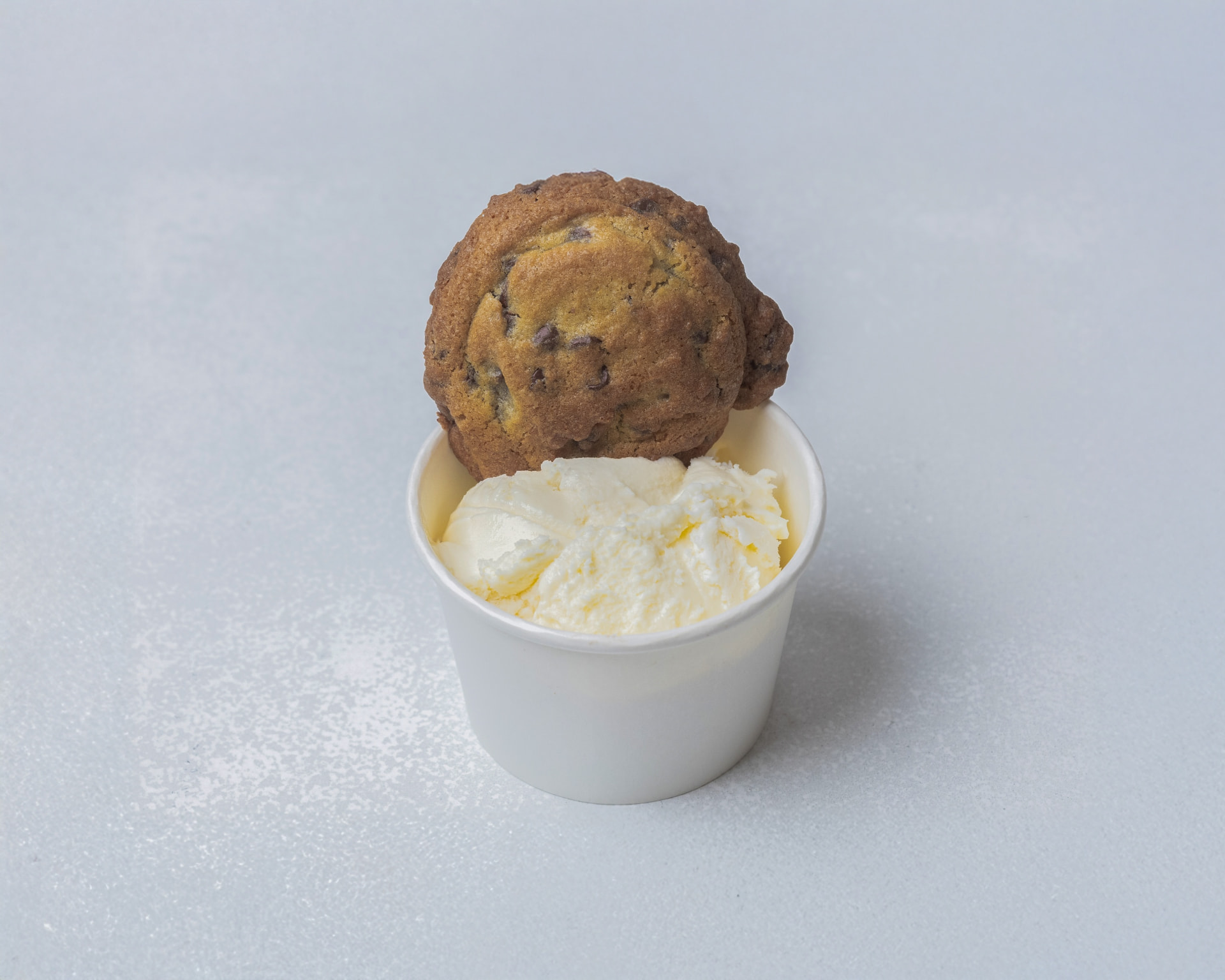 A chocolate chip cookie topped with a scoop of ice cream