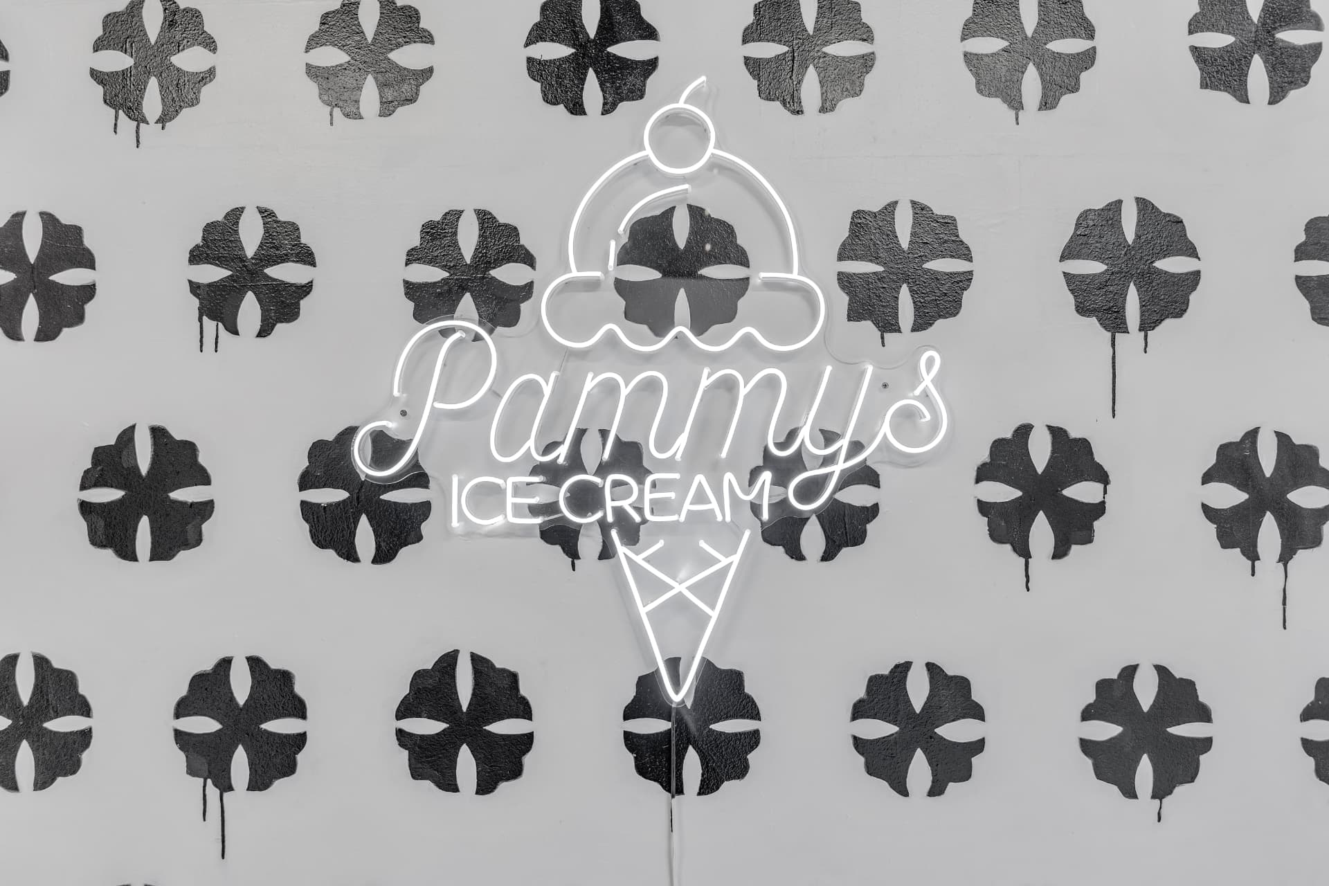 The neon Pammy's Ice Cream cone sign glowing on the hand-painted splatter wall