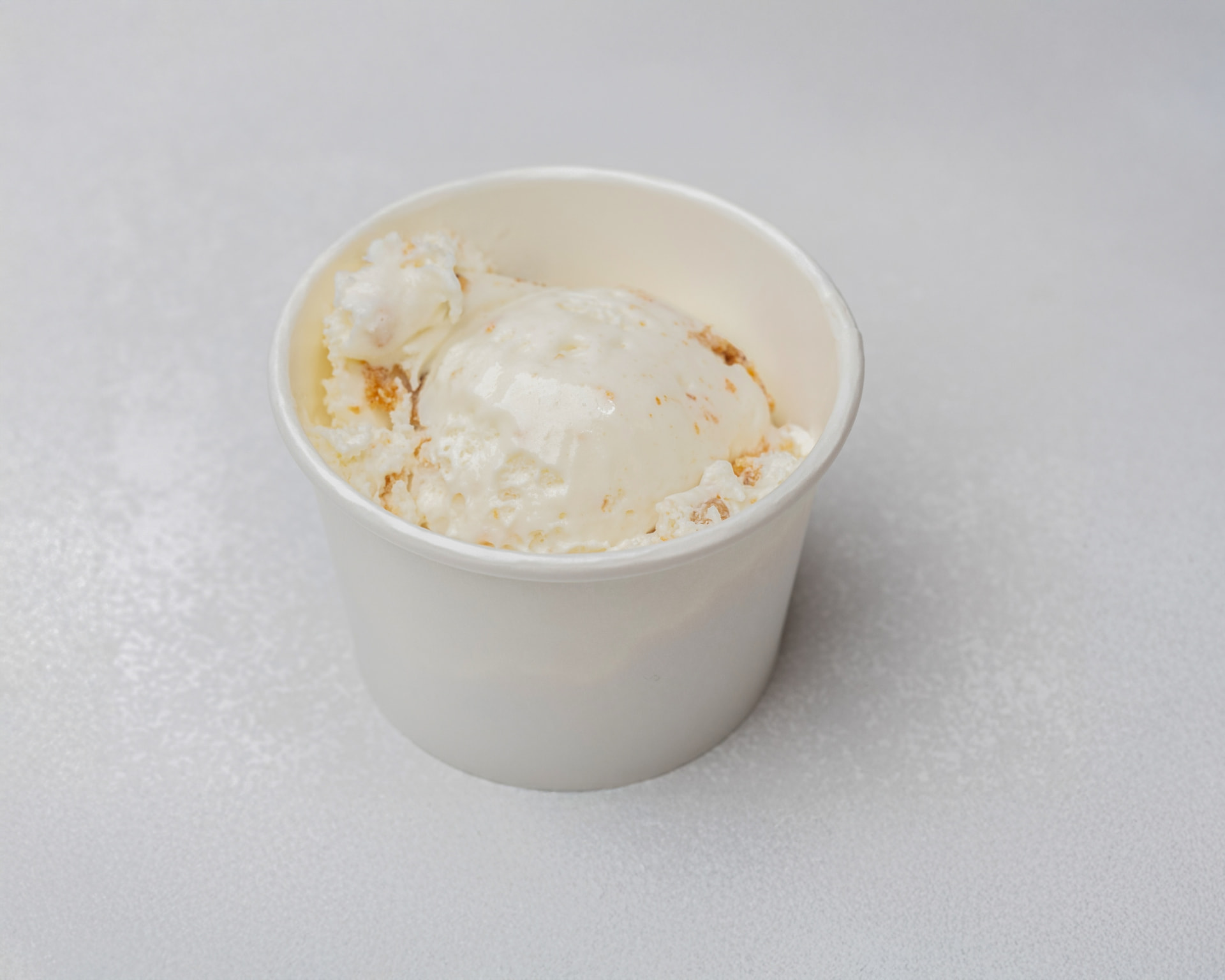 Carrot cake ice cream with cake pieces in a white cup