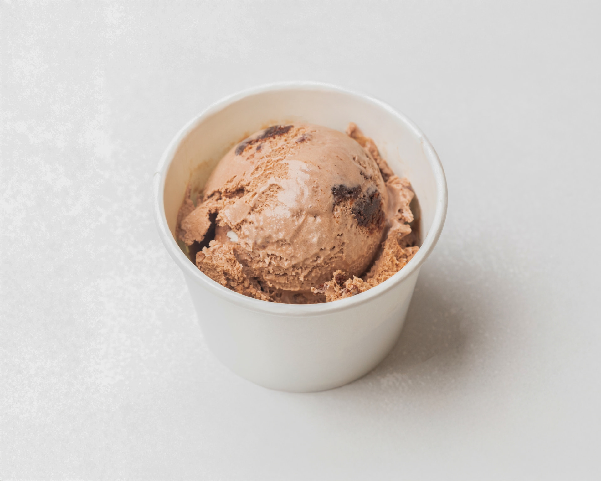 Chocolate brownie ice cream with brownie chunks in a white cup