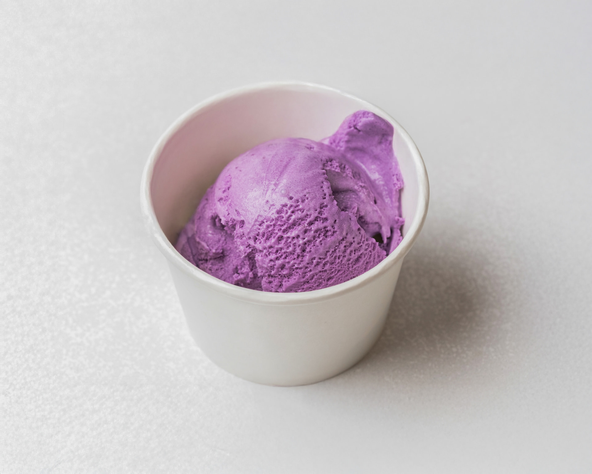 Vivid purple ube ice cream scooped into a white cup at Pammy's Ice Cream