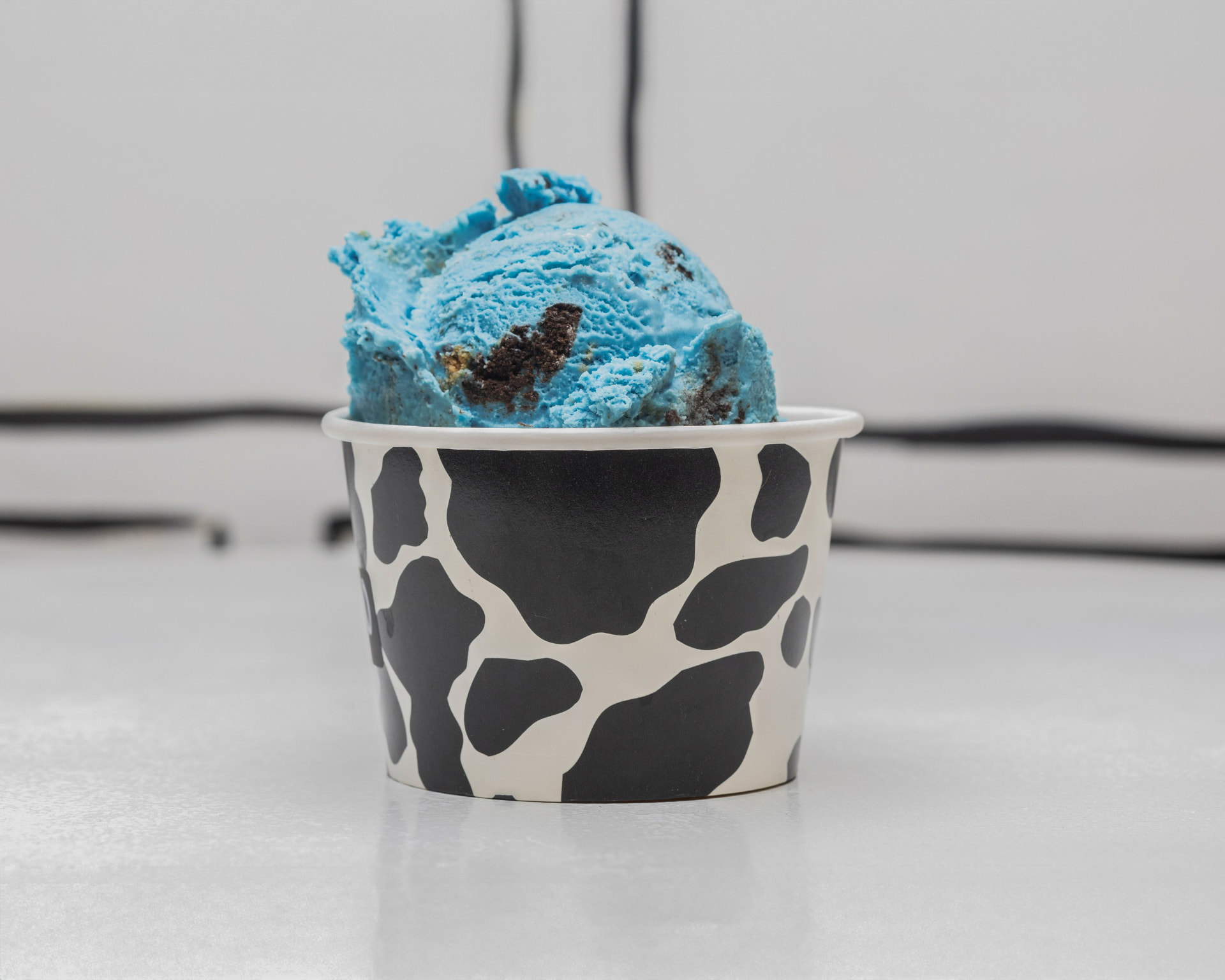 Single scoop of blue Cookie Monster ice cream in a cow-print cup