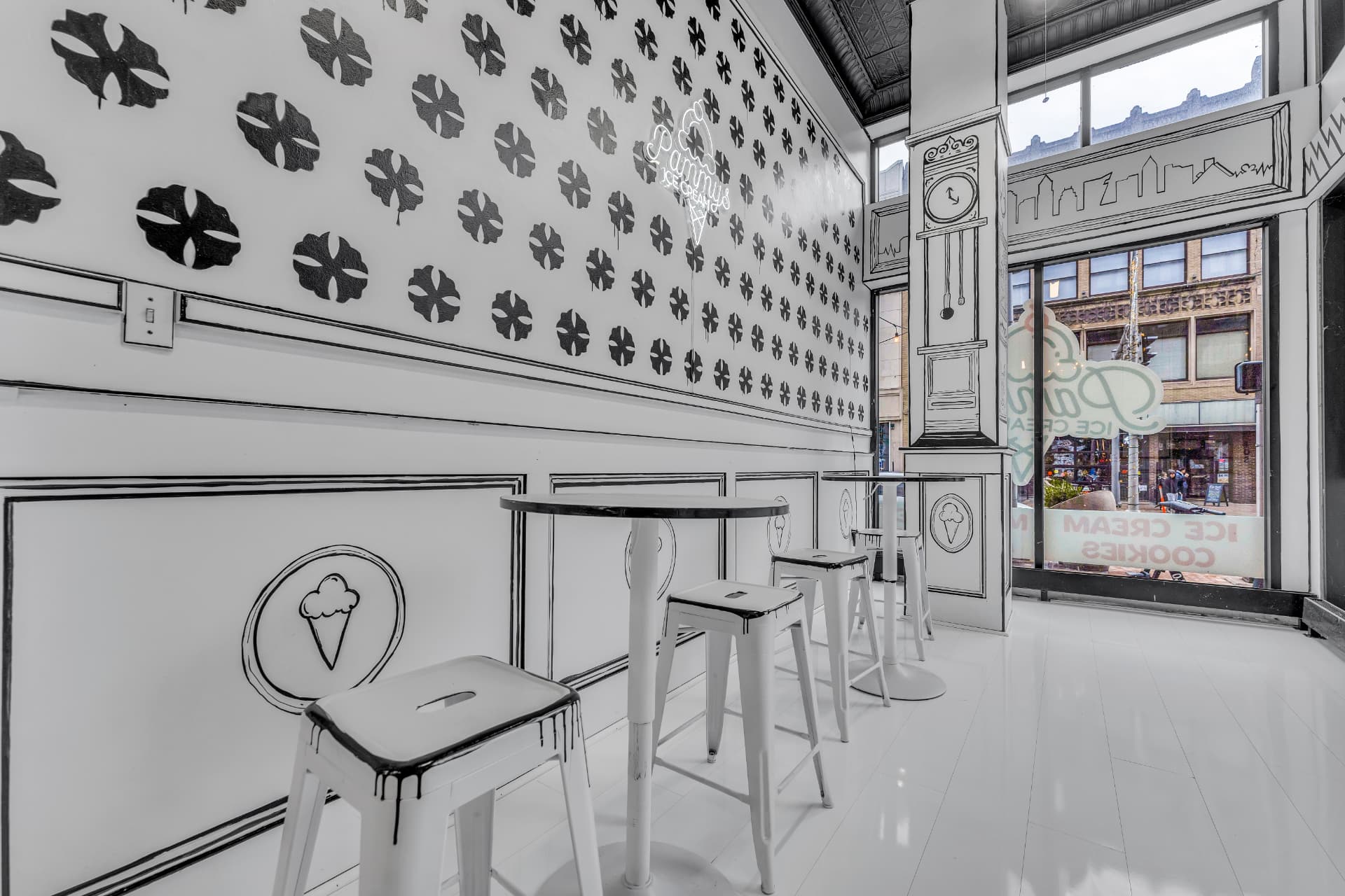 Hand-drawn seating area with white stools, splatter wall and the Cleveland skyline drawn on the window
