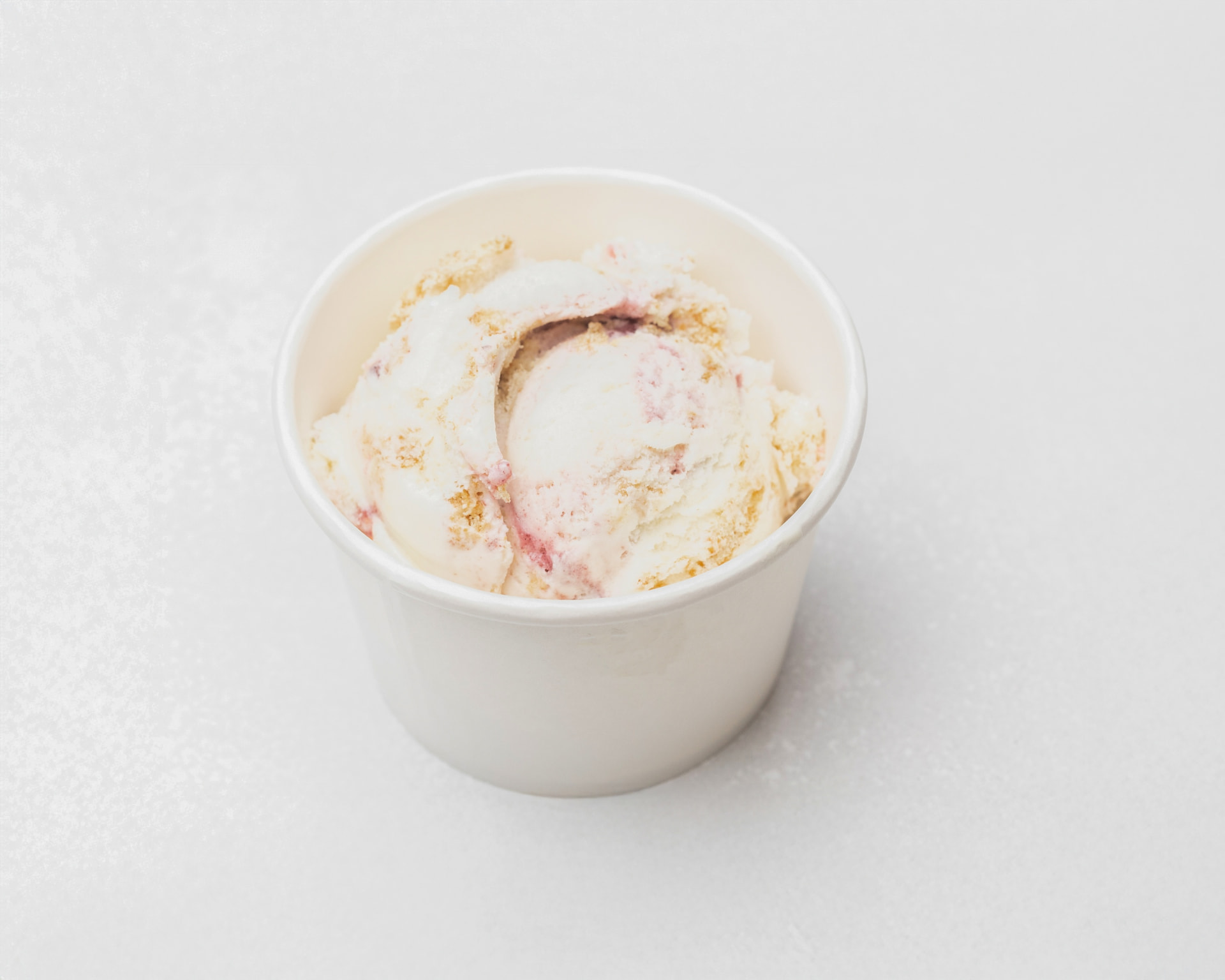 Blueberry cheesecake ice cream with cheesecake pieces in a white cup