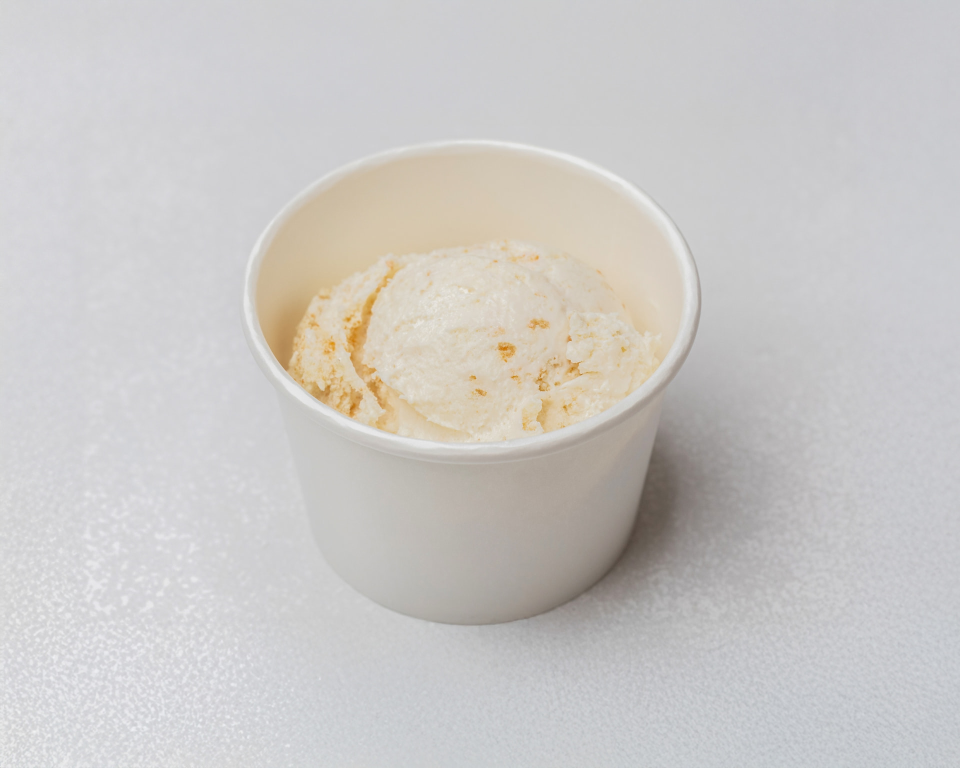 Banana pudding ice cream with cake and wafer pieces in a white cup