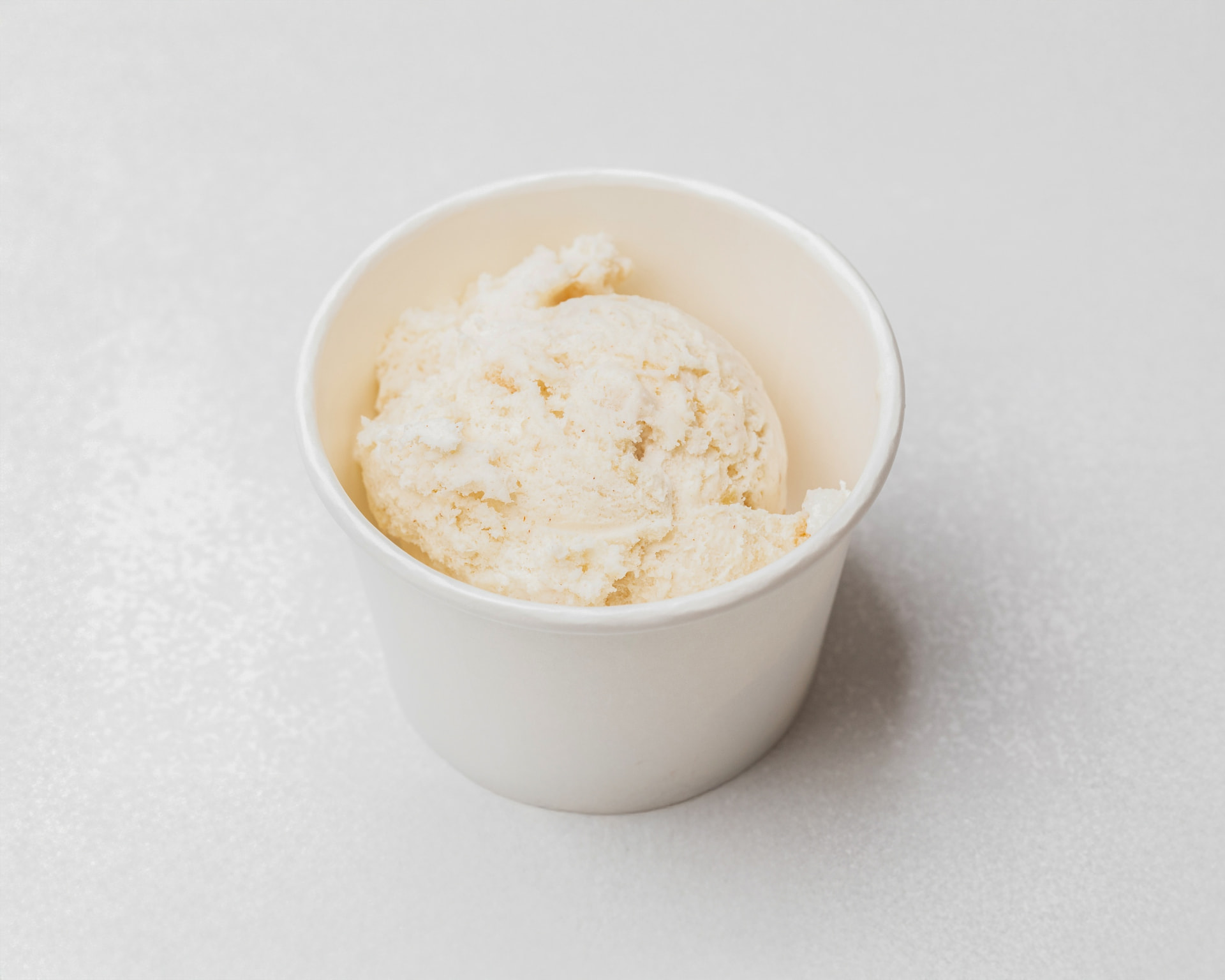 Salted caramel apple pie ice cream with pie pieces in a white cup