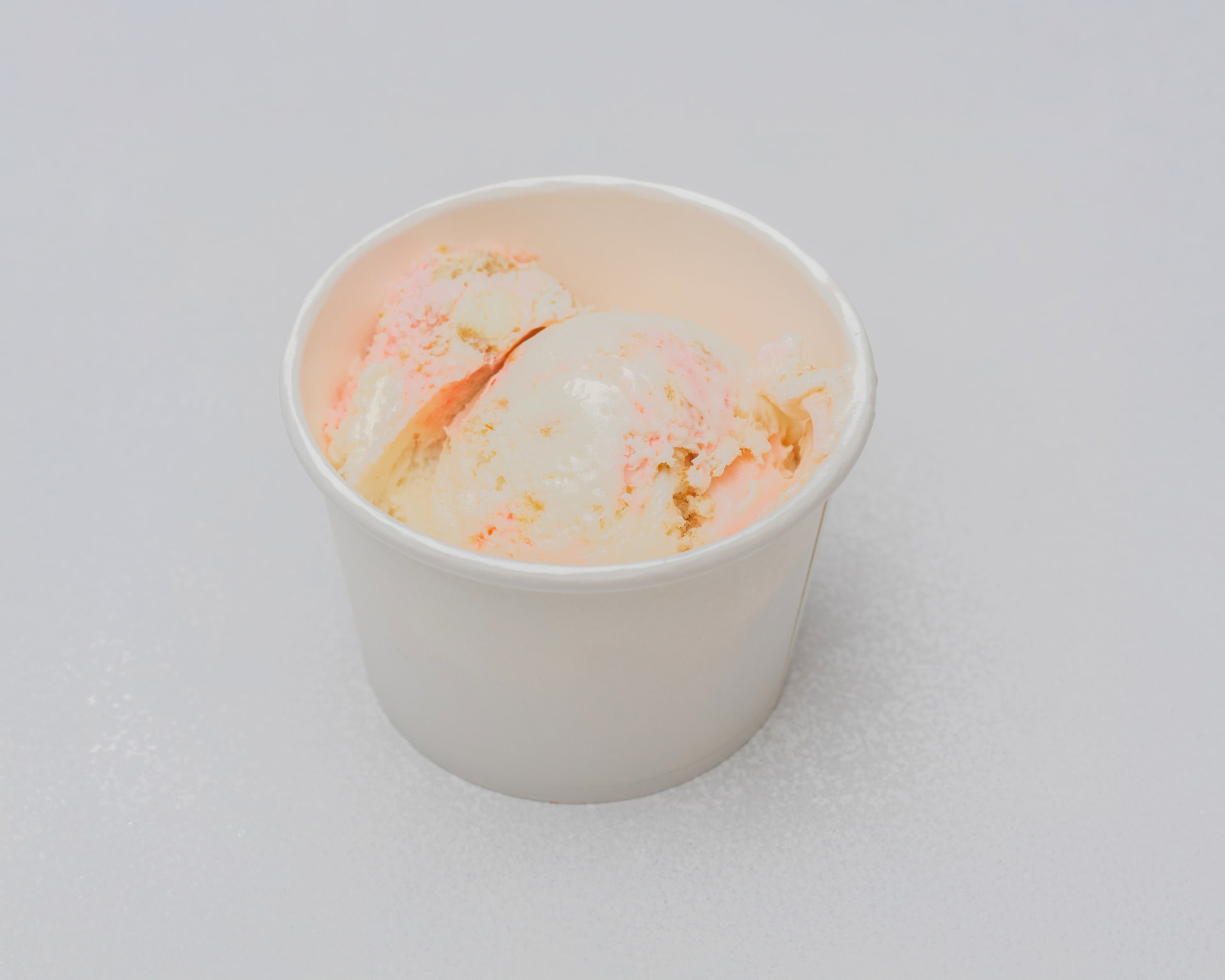 Strawberry cheesecake ice cream with cheesecake pieces in a white cup